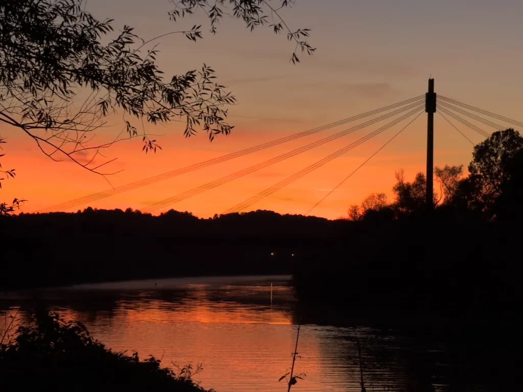Zdjęcie przedstawia zachód słońca nad rzeką Wisłą w Krakowie, w tle widoczny jest balon oraz most im. Marszałka Józefa Piłsudskiego