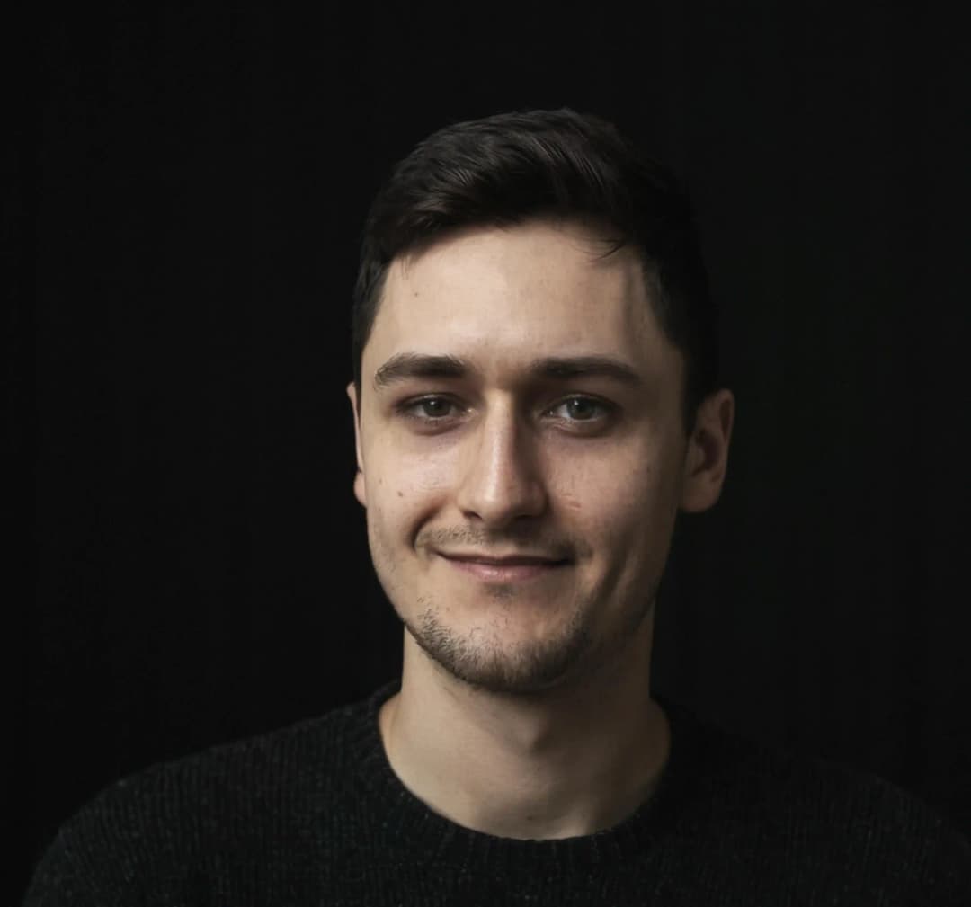 Zdjęcie przedstawia portret Adama Noszczyńskiego w czarnym swetrze i na czarnym tle