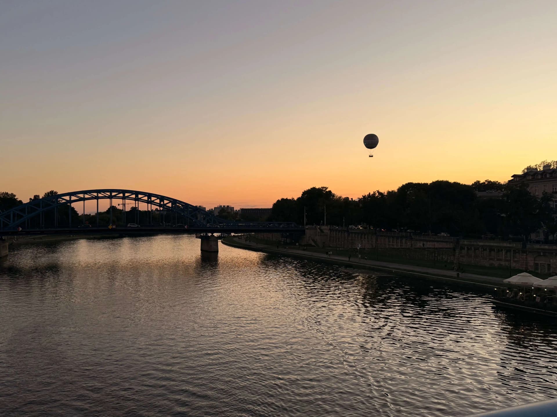 Fotografia Krakowa Zdjęcie przedstawia zachód słońca nad rzeką Wisłą w Krakowie, w tle widoczny jest balon oraz most im. Marszałka Józefa Piłsudskiego