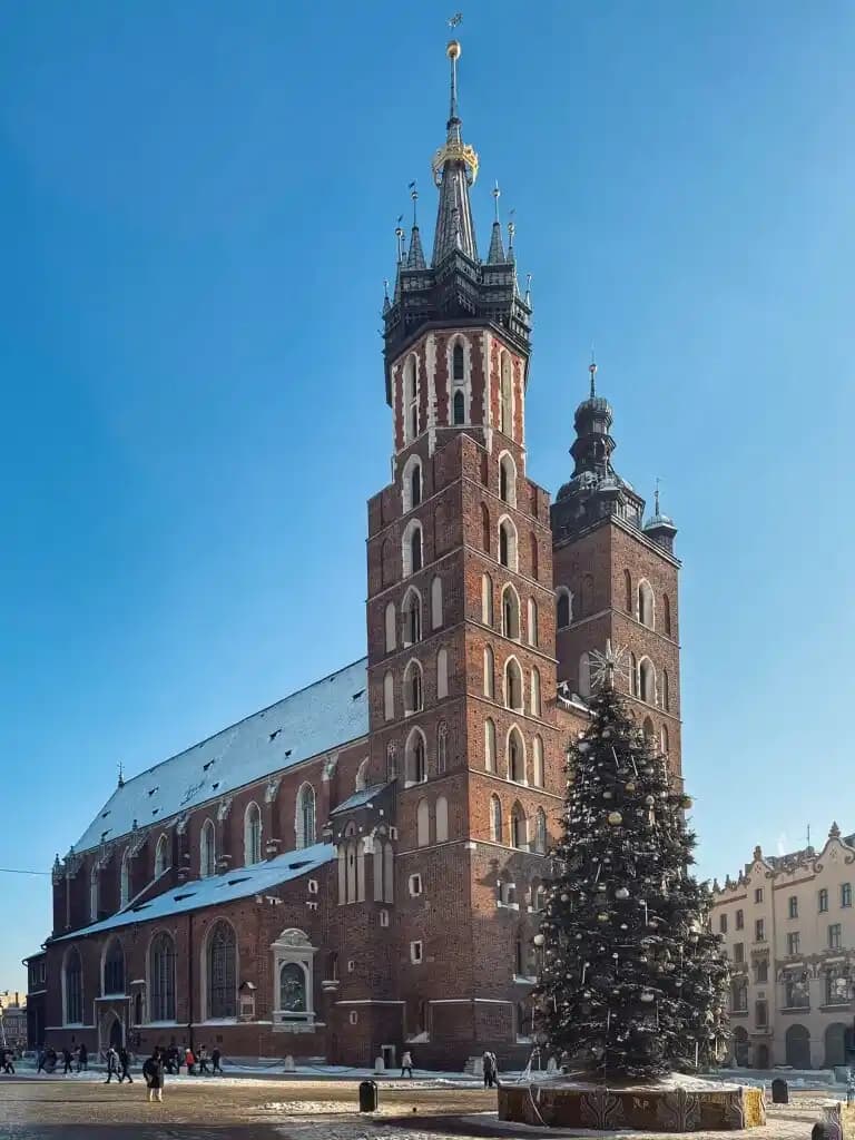 Kościół Mariacki w Krakowie Zdjęcie przedstawia kościół Mariacki w Krakowie widoczny z płyty rynku od lewej strony sukiennic patrząc na katedrę